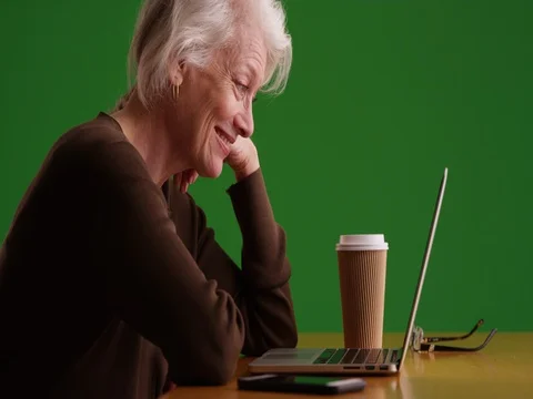 Mature woman scrolling through website on computer laughing on greenscreen Stock Footage