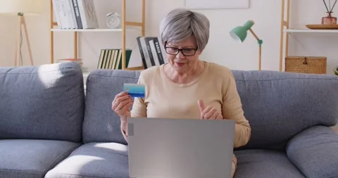 Mature woman using laptop computer and credit card for shopping online making Stock Footage 344984891