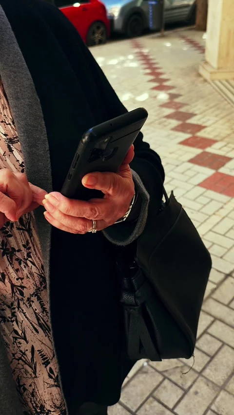 Mature woman using smartphone while walking in the street. Stock Footage 345250434