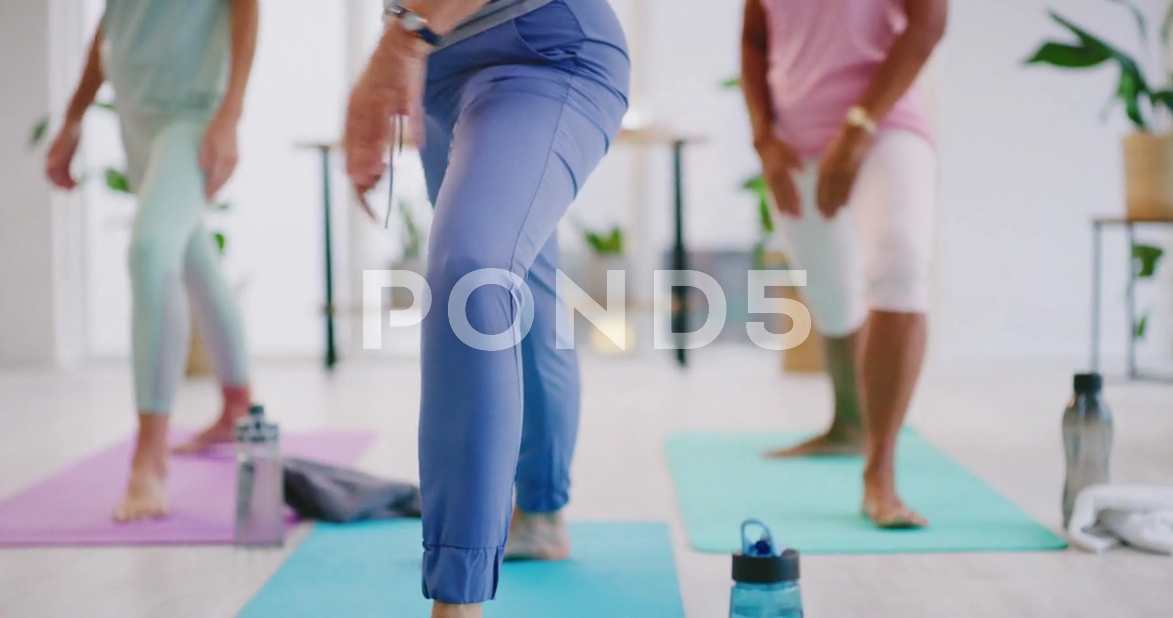 Mature women doing yoga in warrior pose at a fitness center together.  Females