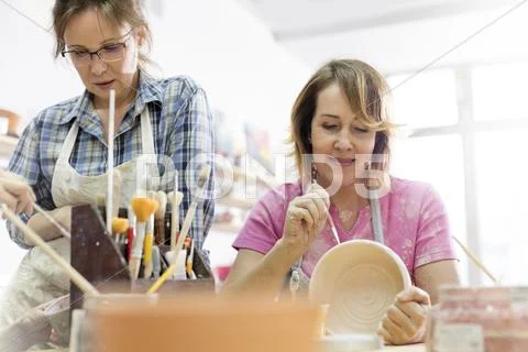 Mature women painting pottery in studio Stock Photos