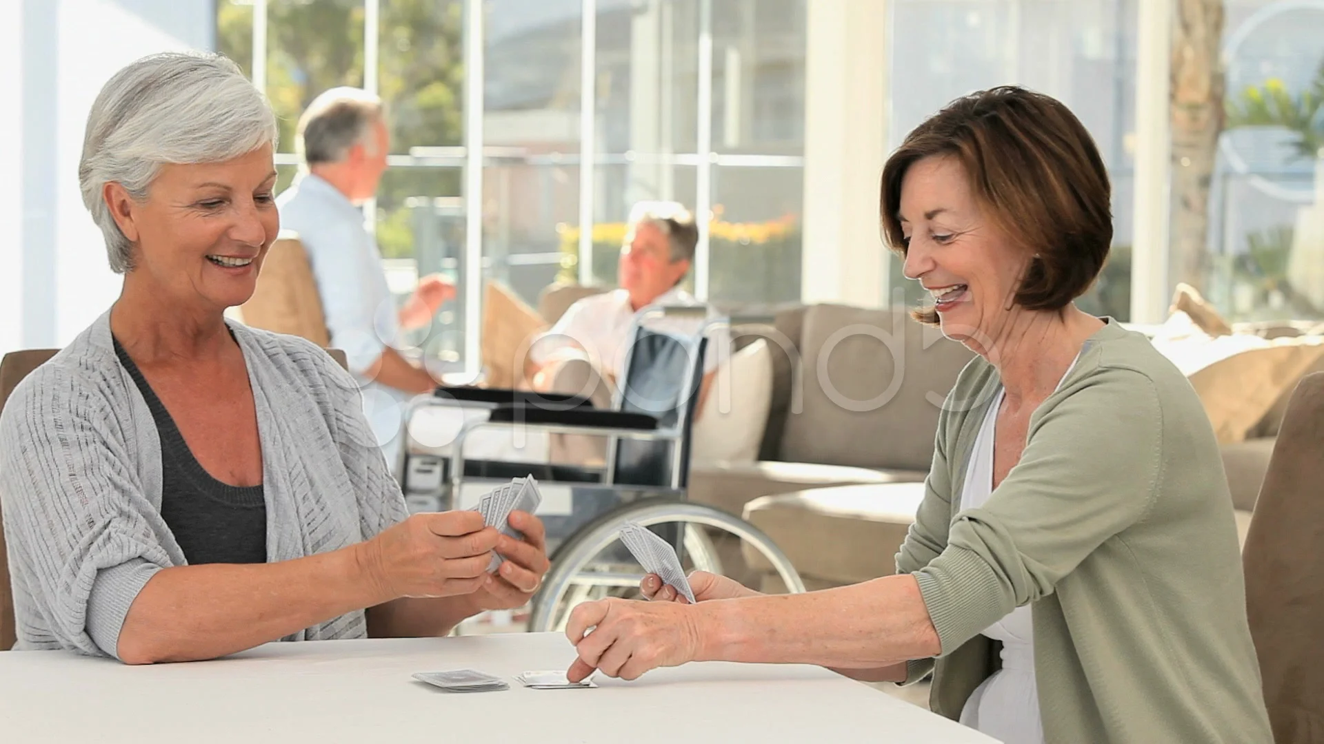 Mature Women playing cards while their husbands are talking