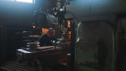 Mature worker looks at drilling machine cutting out holes Stock Footage 243306598