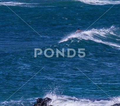Maui surfer and rock with crashing waves at Ho’okipa Stock Photos