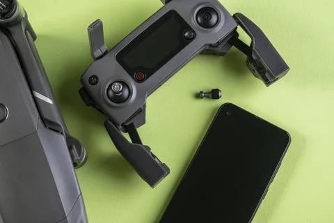 Mavic 2 pro drone, its controller and a smartphone on green background Stock Photos