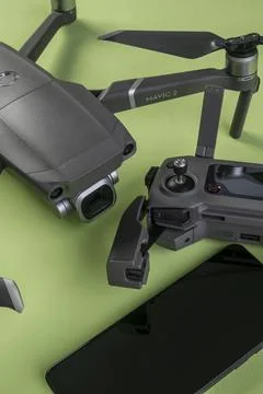 Mavic 2 pro drone, its controller and a cell phone on green background Stock Photos