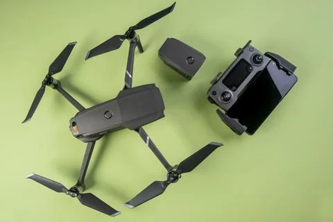 Mavic 2 pro drone, its controller and a smartphone on green background Stock Photos