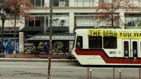 A MAX lightrail crosses in front of Louis Vuitton, downtown Portland, Oregon Stock Footage 144188716