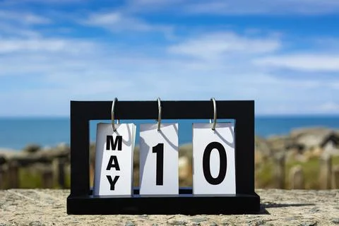May 10 calendar date text on wooden frame with blurred background of ocean. Stock Photos