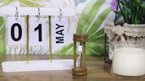 May 1st calendar with candle and flowers near tropical wall on desktop and woman Stock Footage 332296161