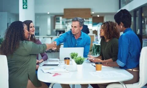 May the best man win. two designers shaking hands during a meeting. Stock Photos