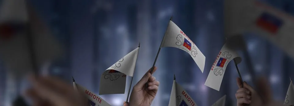 Mayotte flags in their hands on a blurred urban background Stock Photos