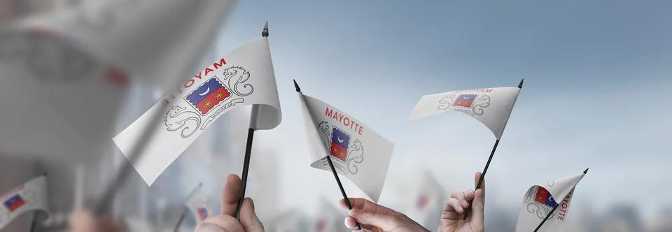 Mayotte flags in their hands on a blurred urban background Stock Photos
