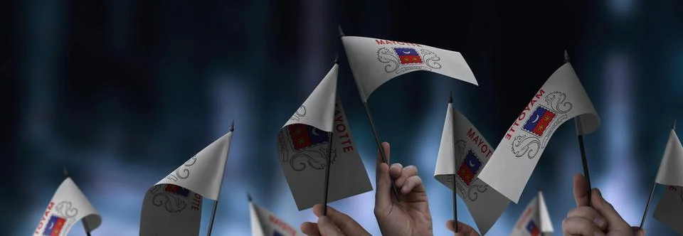 Mayotte flags in their hands on a blurred urban background Stock Photos