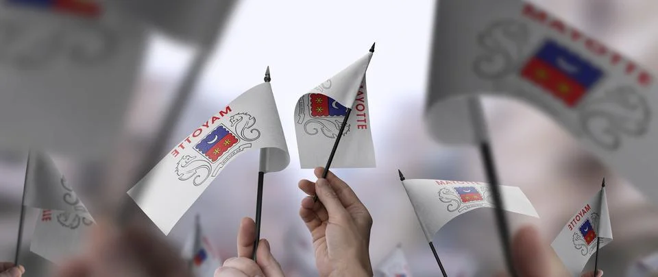 Mayotte flags in their hands on a blurred urban background Stock Photos