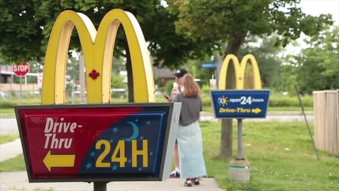 Mcdonalds drive thru signs on posts at entrance with one in front of the other Stock Footage 250279752