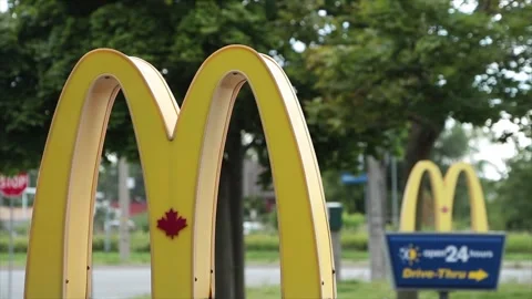 Mcdonalds drive thru signs on posts at entrance with one in front of the other Stock Footage 250279864