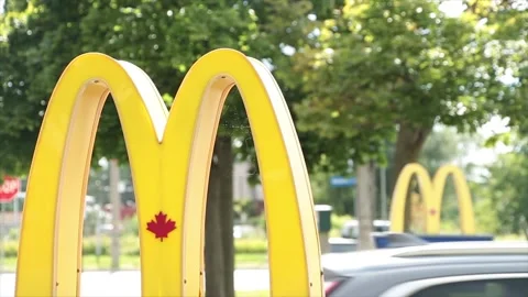 Mcdonalds drive thru signs on posts at entrance with one in front of the other Stock Footage 250279878