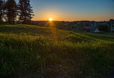 Meadow with a setting sun in the background Stock Photos