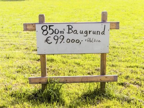 On a meadow is a sign for a building plot for a house for sale. Building site Fotos de archivo