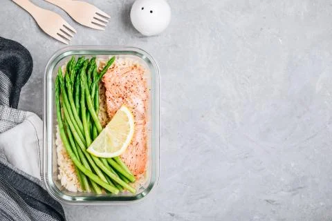 Meal prep lunch box container with baked salmon fish, rice, green asparagus Stock Photos