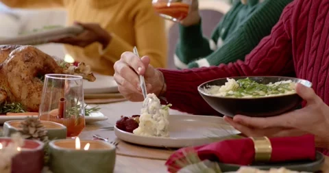 As meal is starting, red sweater server is scooping mashed potatoes onto plate Stock Footage 345607389