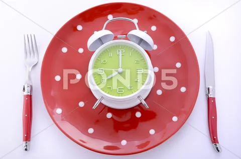 Mealtime table place setting with alarm clock Stock Photos