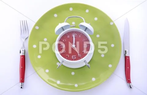Mealtime table place setting with alarm clock Stock Photos