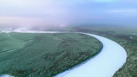 Meandering frozen river flowing through a snowy forest wilderness Stock Footage 337026326