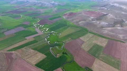 Meandering river winds through patchwork farmland - Green Fields and Cultivated Stock Footage 339574729