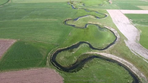 Meandering river winds through patchwork farmland - Meadow and Serpentine Creek Stock Footage 339574979