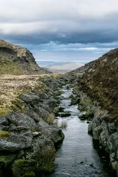 A meandering stream traces a path through a valley Stock Photos
