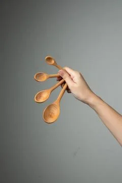 Measure spoon table spoon tea spoon in hand grey background Stock-Fotos