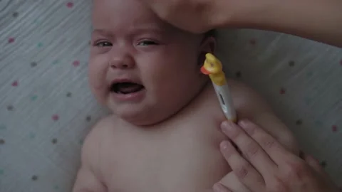 Measure temperature electronic thermometer to upset crying and sobbing newborn Stock Footage 138056183