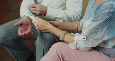 Measures temperature with contactless digital thermometer. Senior couple Stock Footage 145832417