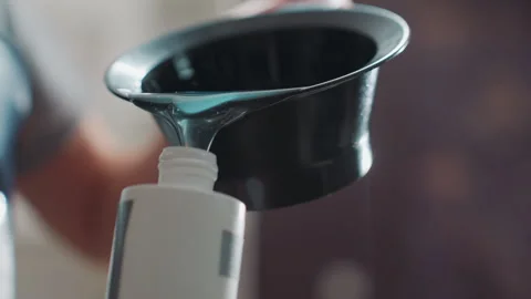 Measuring and carefully pouring solution into funnel at salon, worker carefully Stock Footage 323116466