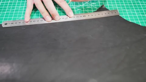 Measuring and cutting leather by a tanner in a workshop using a ruler and tools Stock Footage 329022064