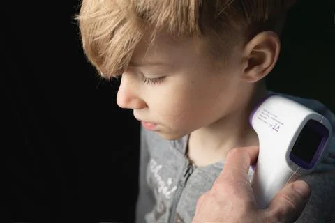 Measuring boy's temperature using non contact device infrared thermometer gun Stock Photos