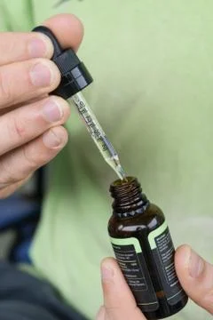 Measuring the correct amount of cbd oil from a brown tincture bottle. Stock Photos