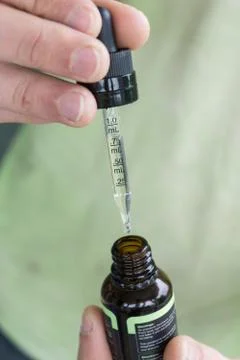 Measuring the correct amount of cbd oil from a brown tincture bottle. Stock Photos