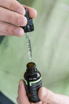 Measuring the correct amount of cbd oil from a brown tincture bottle. Stock Photos