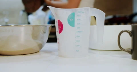 A measuring cup in ml on the kitchen table. Measuring weight of the ingredients Stock Footage 148016957