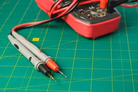 Measuring electric current with multimeter and test leads on green mat Stock Photos