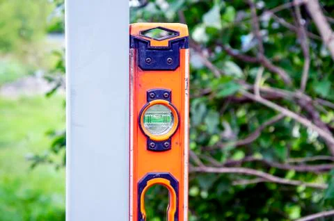 Measuring the level of installation of a metal post with a building level. Fe Stock Photos