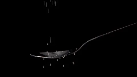 Measuring one tablespoon cane or brown sugar powder on a spoon, black background Stock Footage 170433046