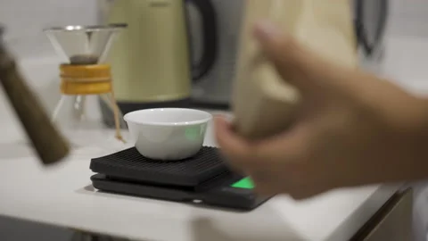 Measuring out coffee beans on a kitchen scale with a fancy spoon Stock Footage 132887317