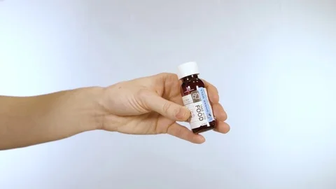 Measuring out liquid medication from bottle with take with food label Stock Footage 72163356