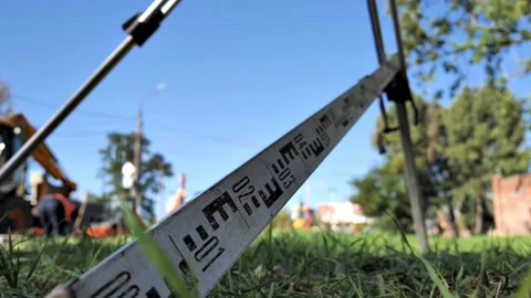 A measuring rail is attached to the tripod of a  level Stock Footage 219633382