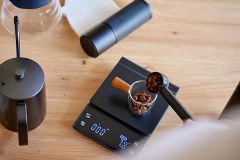 Measuring roasted coffee beans on digital scale for brewing Stock Photos