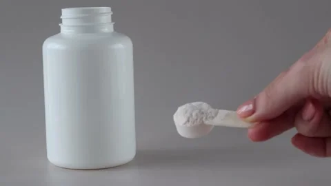 Measuring spoon with electrolyte powder and sports nutrition in the hand of a Stock Footage 234984840